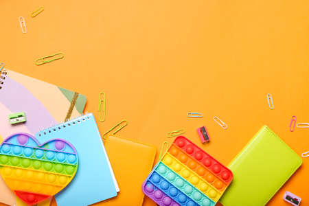 Pop it fidget toys and stationery on color background