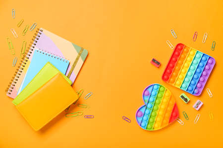 Pop it fidget toys and stationery on color background