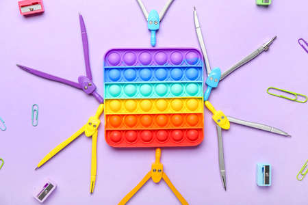 Pop it fidget toy and stationery on color background