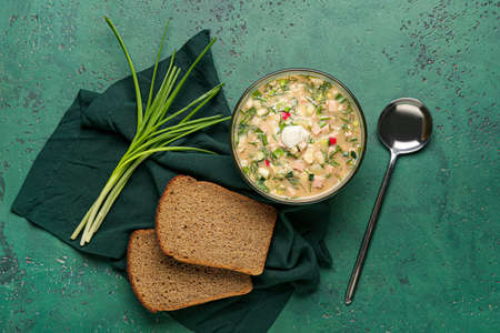 Bowl with tasty okroshka, bread and green onion on color backgroundの写真素材