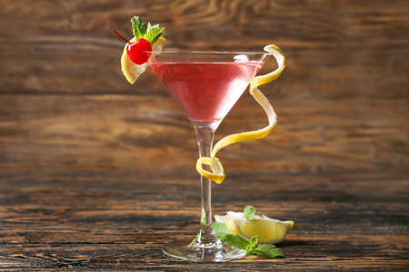 Glass of tasty cosmopolitan cocktail on wooden background