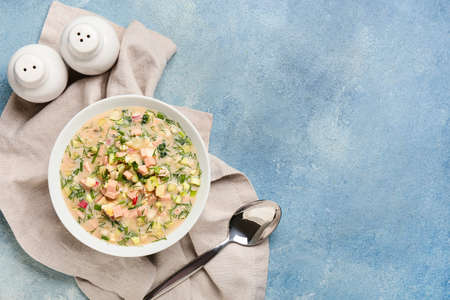 Bowl with tasty okroshka, spoon and spices on color backgroundの写真素材