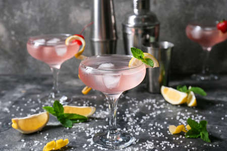Glasses of tasty cosmopolitan cocktail, slices of lemon, mint and sea salt on dark backgroundの写真素材