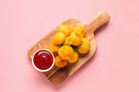 Board with fried potato balls and sauce on color backgroundの写真素材