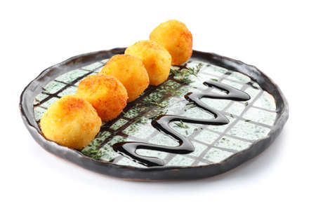 Plate with fried potato balls on white background