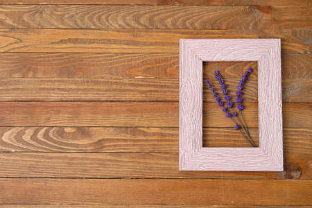 Beautiful lavender flowers and empty picture frame on wooden backgroundの写真素材