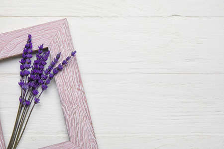 Beautiful lavender flowers and empty picture frame on light wooden backgroundの写真素材