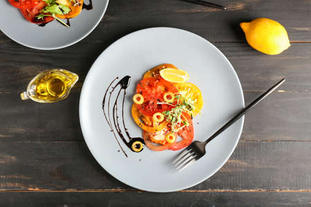 Plates with tasty tomato carpaccio, oil and lemon on dark wooden backgroundの写真素材