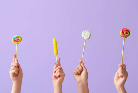 Women holding sweet lollipop on lilac backgroundの写真素材