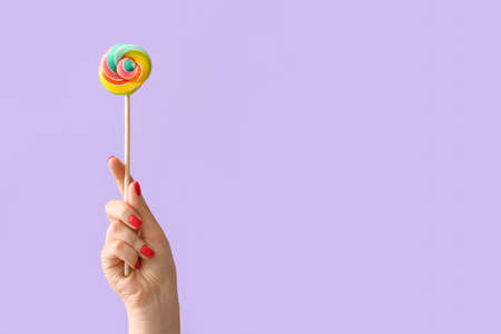 Woman holding lollipop on lilac backgroundの写真素材
