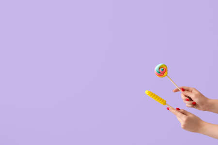 Woman holding sweet lollipops on lilac backgroundの写真素材