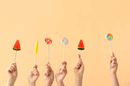 Women holding different sweet lollipops on beige backgroundの写真素材