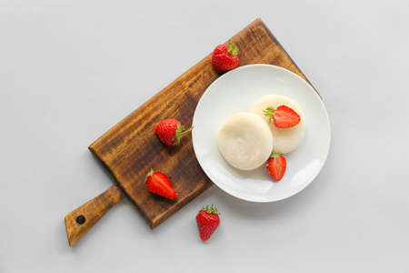 Plate with tasty Japanese mochi and strawberry on light background