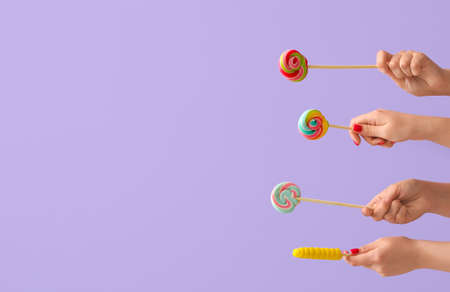 Women holding sweet lollipop on lilac backgroundの写真素材
