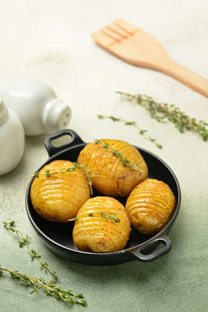 Frying pan with baked potato on color background