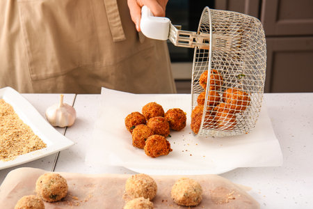 Woman with prepared code cutlets in the kitchen
