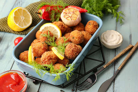 Baking dish with tasty cod cutlets and sauces on color wooden backgroundの写真素材