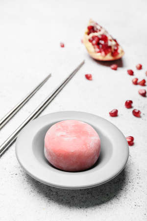 Plate with delicious mochi, pomegranate and chopsticks on grunge background