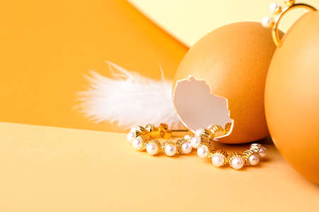 Eggshell and stylish pearl earrings on color background