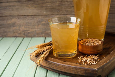 Glass and jug of fresh kvass on color wooden backgroundの写真素材