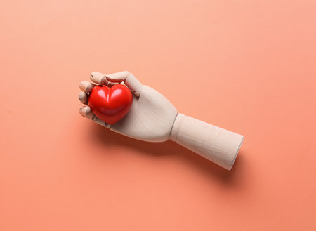 Wooden hand with red heart on color background. Donation conceptの写真素材