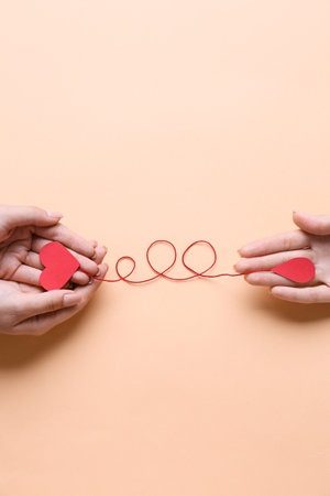 Female hands with red paper heart and drop of blood on color background. Donation conceptの写真素材