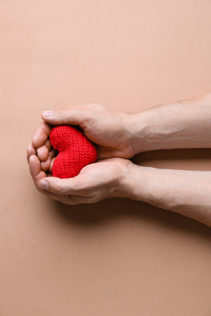 Male hands with knitted heart on color background. Donation conceptの写真素材