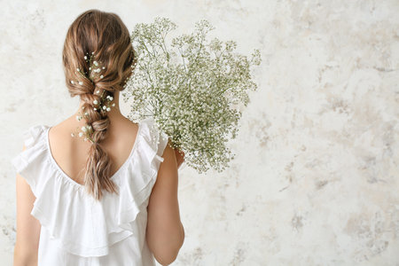 Pretty young woman with bouquet of flowers on light backgroundの写真素材