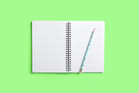 Open notebook and pencil on color background