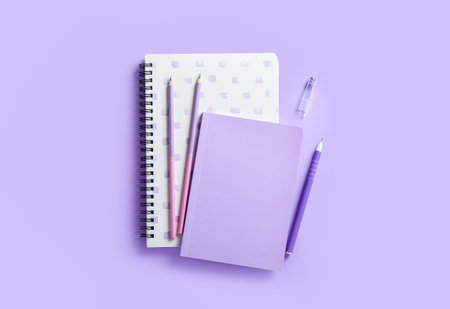 Stylish notebooks, pen and pencils on color backgroundの写真素材