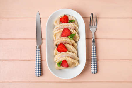 Plate with tasty strawberry dumplings on color wooden backgroundの写真素材