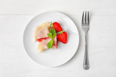 Plate with tasty strawberry dumplings on light wooden backgroundの写真素材