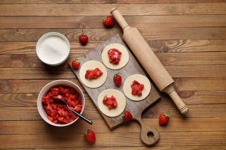 Composition with raw dough for dumplings and strawberry on wooden backgroundの写真素材