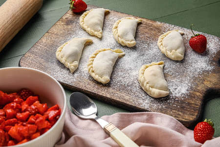 Composition with raw dumplings and strawberry on color wooden backgroundの写真素材