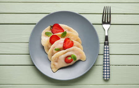 Plate with tasty strawberry dumplings on color wooden backgroundの写真素材