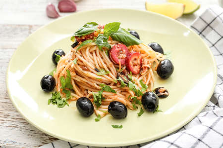 Plate of tasty Pasta Alla Puttanesca on white wooden backgroundの写真素材