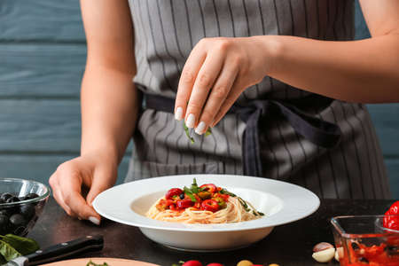 Woman preparing Pasta Puttanesca at kitchen table, closeupの写真素材