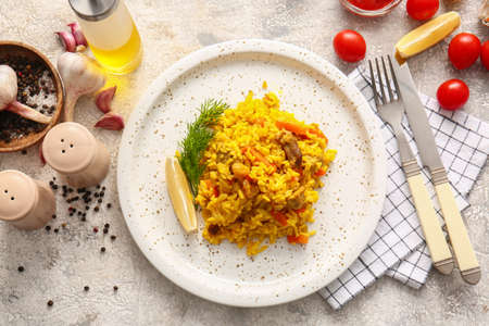 Plate with tasty pilaf on light background