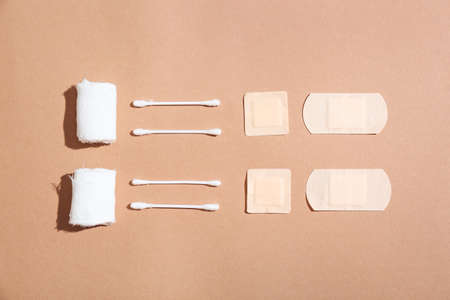 Gauze rolls, cotton buds and medical plasters on color background