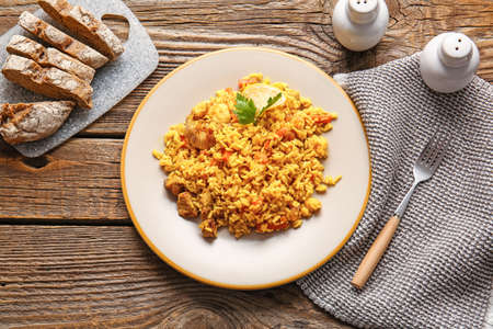 Plate with tasty pilaf on wooden background