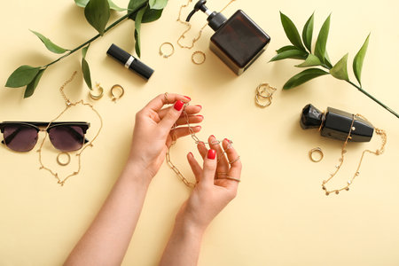 Woman with beautiful manicure holding necklace and different accessories on color backgroundの写真素材