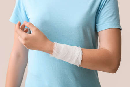 Woman with bandaged hand on color background, closeupの写真素材
