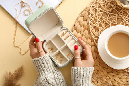 Female hands with beautiful manicure holding jewelry box on color background