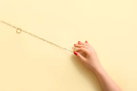 Woman with beautiful manicure holding necklace on color backgroundの写真素材