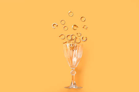 Composition with overturned glass and stylish jewelry on color background