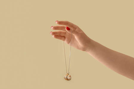 Young woman with beautiful manicure holding stylish necklace on color backgroundの写真素材