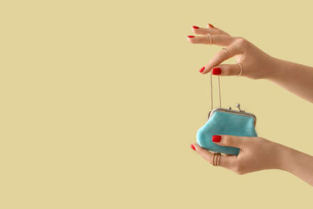 Young woman with beautiful manicure taking necklace out of small purse on color backgroundの写真素材
