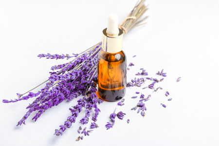 Bottle of lavender essential oil and flowers on light backgroundの写真素材