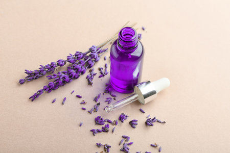 Bottle of lavender essential oil and flowers on color backgroundの写真素材