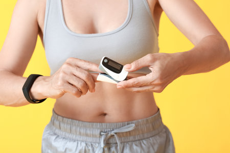 Female runner with pulse oximeter on color background, closeup